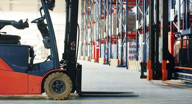 Forklift being prepared to safely load and unload cargo from a flatbed trailer truck, inside a logistics company’s warehouse