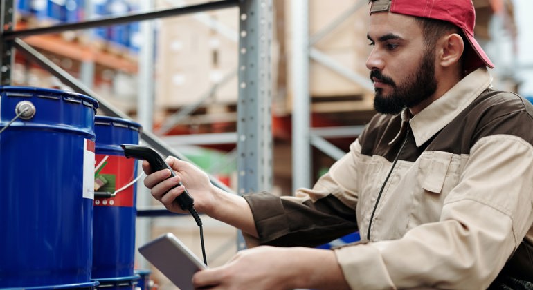 Logistics company employee preparing to safely load a flatbed trailer by inspecting the cargo they will transport on a truck